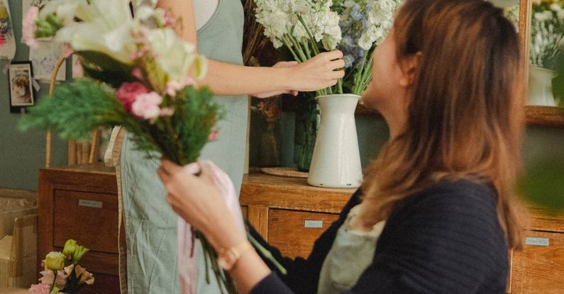 Job Market - Side view of glad colleagues preparing blooming floral decorations while working in stylish florist workshop