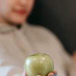 Ethical Dilemmas - Blurred woman showing a green apple and holding a doughnut