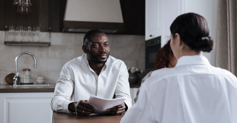 Corporate Social Responsibility - Afro-American Man and Caucasian Woman Having Meeting at Home with Social Worker